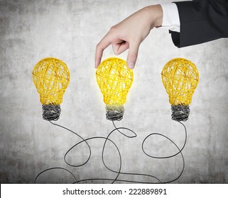 A Hand Chooses One Lightbulb Out Of Three Other. A Metaphor Of The Right Decision. 