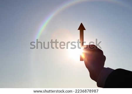 Hand choosing and holding an arrow rising high and stocks finance economy industry growth investment target success concept
