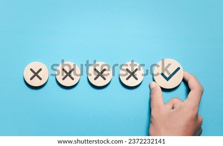 Hand choosing wooden block with correct sign mark and leave the crosshairs option. Approve and reject business project proposal concept.
