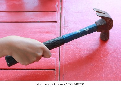 Hand With Claw Hammer Knock On The Red Wood Table