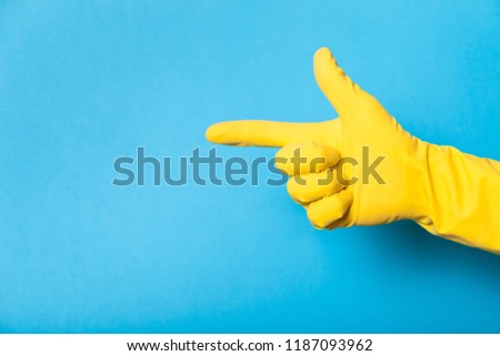 Hand in clean yellow glove, bathroom. Copy space for text.