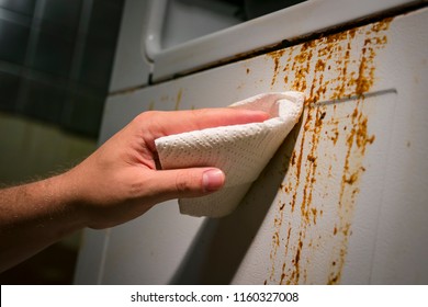 Hand Cleaning Baked On Kitchen Grime On Side Of Oven Appliance, Using Paper Towel And Cleaner.