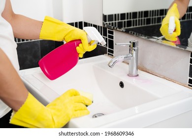 Hand Cleaning Bathroom Sink With Spray Detergent And Sponge