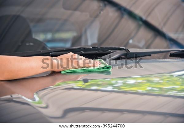 Hand with\
cleaning car with green microfiber\
cloth