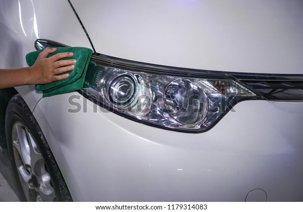 hand cleaning\
car headlight with rag outdoors\
