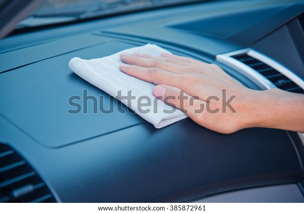 Hand cleaning the car interior with gray microfiber\
cloth 
