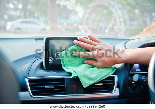 Hand cleaning the car interior with green\
microfiber cloth\
