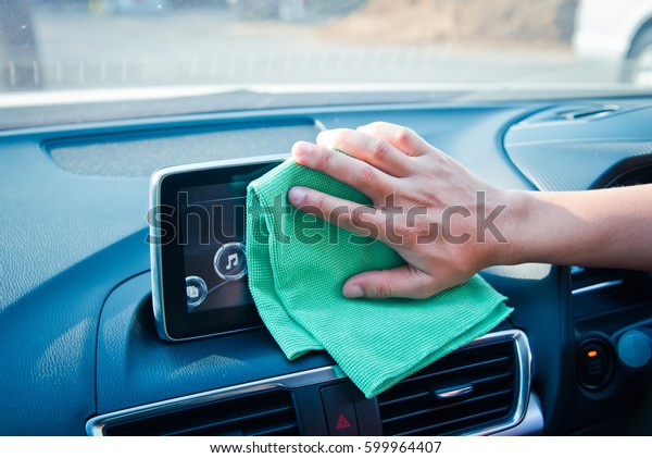 Hand cleaning the car interior with green\
microfiber cloth\
