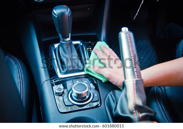Hand cleaning the car interior with green\
microfiber cloth