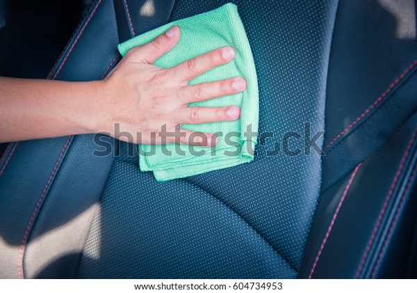 Hand cleaning the car interior with green microfiber\
cloth \
