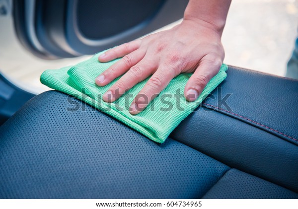 Hand cleaning the car interior with green microfiber\
cloth 