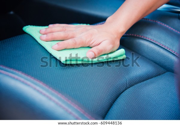 Hand cleaning the car interior with green\
microfiber cloth