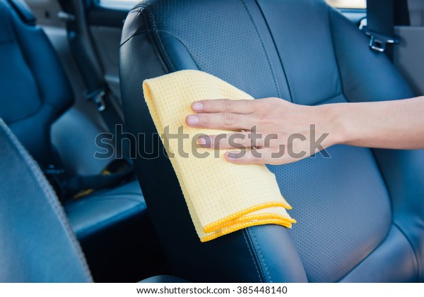 Hand cleaning the car interior with yellow\
microfiber cloth