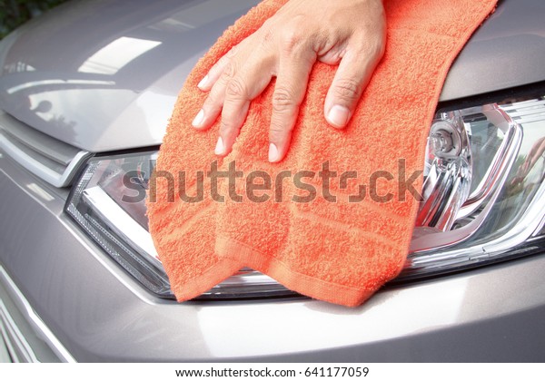 Hand cleaning light\
car with orange cloth