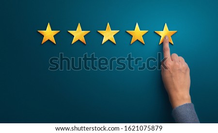 Hand of client giving a five star rating on blue background, panorama, copy space. Service rating, satisfaction concept