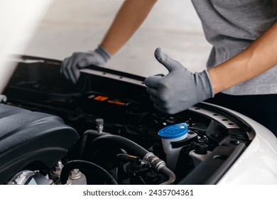 Hand of client showing thumb up for approval of car repair work, Mechanic working under the hood of car. - Powered by Shutterstock