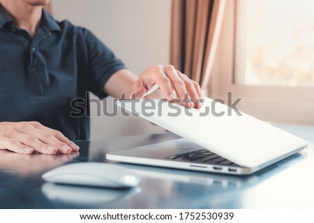 Hand close or open laptop on the table at home