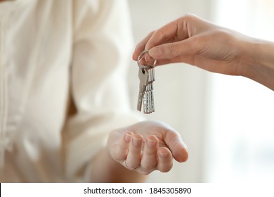 From Hand To Hand. Close Up Shot Of Hand Of Female Seller Owner Of House Apartment Office Holding Keys Giving It To Young Woman Buyer Renter After Conclusion Of Successful Deal And Getting Downpayment