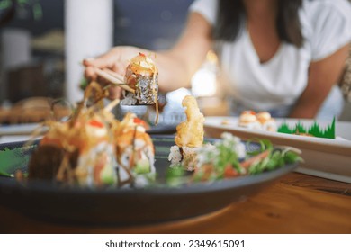 Hand, closeup and chopsticks in sushi restaurant for diet, fine dining and party with catering platter. Person, healthy fish and salmon with culture, traditional or fast food in diner, bar or store - Powered by Shutterstock