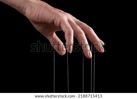Hand closeup pulling strings, manipulating, controlling. Authority concept. High quality photo