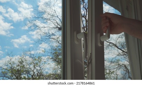 Hand Closing Or Opening Window, Behind Which You Can See Blue Sky With Clouds.