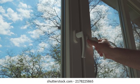 Hand Closing Or Opening Window, Behind Which You Can See Blue Sky With Clouds.