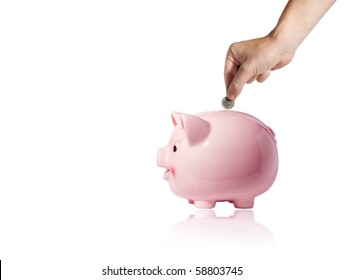 Hand With Coin Over A Piggy Bank On White Background With Reflection