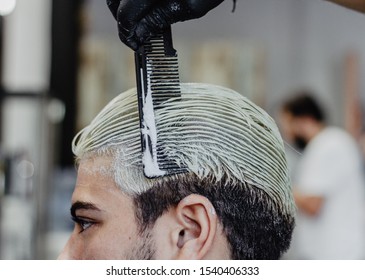 Hairdresser´s hand combing the dyed hair of a young man in a Barber Shop. - Powered by Shutterstock