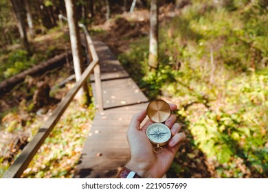 Hand With Compass In Forest Terrain. POV Travel Concept.