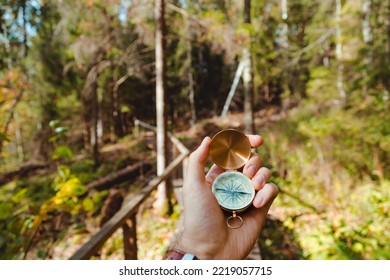 Hand With Compass In Forest Terrain. POV Travel Concept.