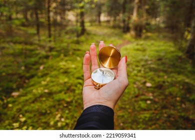 Hand With Compass In Forest Terrain. POV Travel Concept.