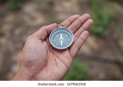 Hand with compass at mountain road at brown ground - Shutterstock ID 1079041958