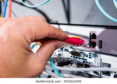 Hand of computer technician connecting patch cable into data switch