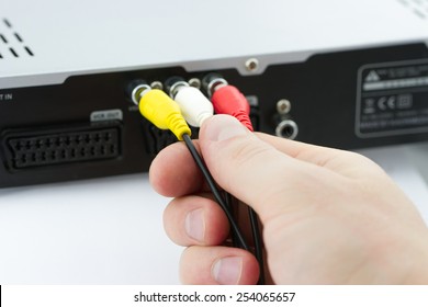 Hand connecting AV cables to AV Receiver