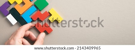 hand connecting geometric shape block with colorful wood puzzle pieces