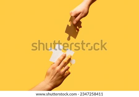 Hand connecting jigsaw puzzle. Man hands connecting couple puzzle piece. Closeup hands of man connecting jigsaw puzzle. Two hands trying to connect couple puzzle with yellow background.