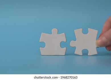 Hand Connecting Puzzle Pieces Representing The Merging Of Two Companies Or Joint Venture. Partnership And Acquisition Concept.