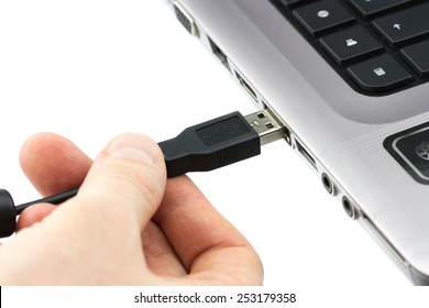 Hand connecting USB cable to laptop computer isolated on white background
