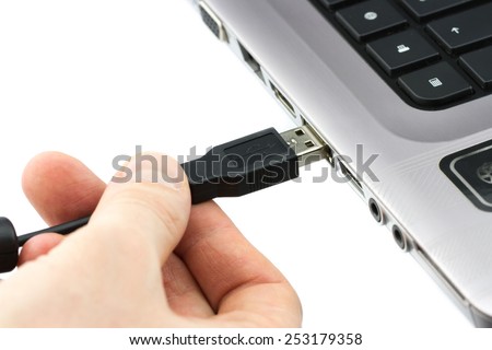 Hand connecting USB cable to laptop computer isolated on white background