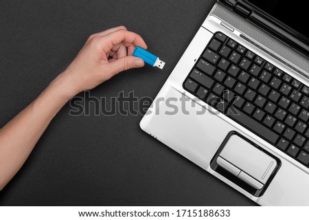 Hand connecting usb flash drive to notebook.
