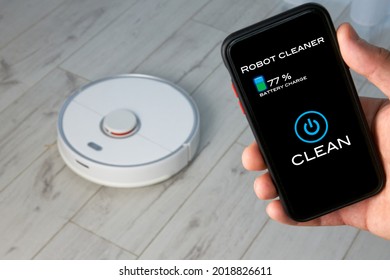 Hand control of the robot vacuum cleaner in the app on the mobile phone screen. One-touch home cleaning