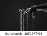 Hand with Controlling Strings, Manipulation Concept in Black and White on Textured Paper Background