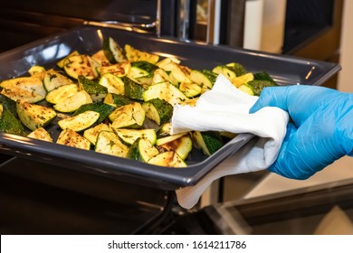 Hand Of The Cook Takes Out From The Oven A Sheet Of The Tray With Fried Zucchini In Olive Oil. Cooking A Dish Of Vegetables. Close Up