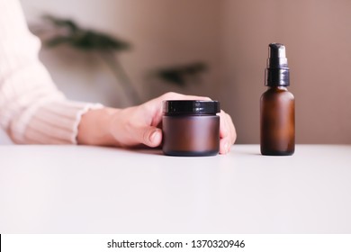 hand with cosmetic cream lotion .Beauty skincare background .Products with flower ,leaves . pink minimal concept table top view, flat lay.