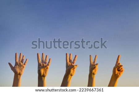 Hand countdown concept. Counting down on blue background. Gesturing number 5, 4, 3, 2, 1. Number five, four, three. two and one in sign language. Copy space for ad text. 