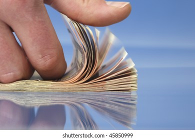 Hand Counting Money, Closeup On Blue Background With Reflections