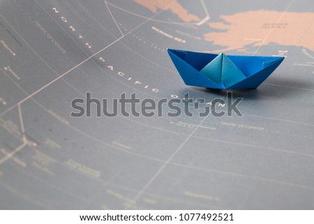 Hand crafted paper boat on worldmap background