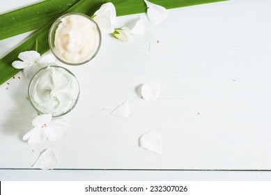 Hand Cream And Face Cream With White Flowers On Bright Wooden Table