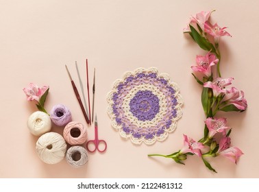 Hand crochet a delicate round lace doily and fresh alstroemeria flowers on pink pastel background. Handmade gift for spring holidays. DIY concept. Flat lay, copy space, close up, top view, mock up