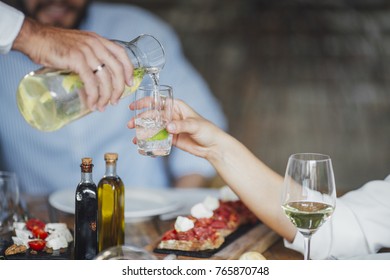 Hand of cropped unrecognisable man ouring drink to woman at lunch. - Shutterstock ID 765870748